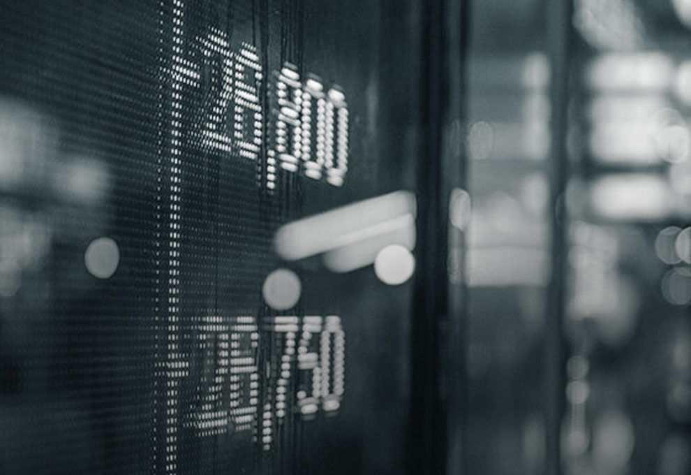 Digitale Anzeigetafel mit leuchtenden Kurszahlen und Aktienwerten im unscharfen Hintergrund