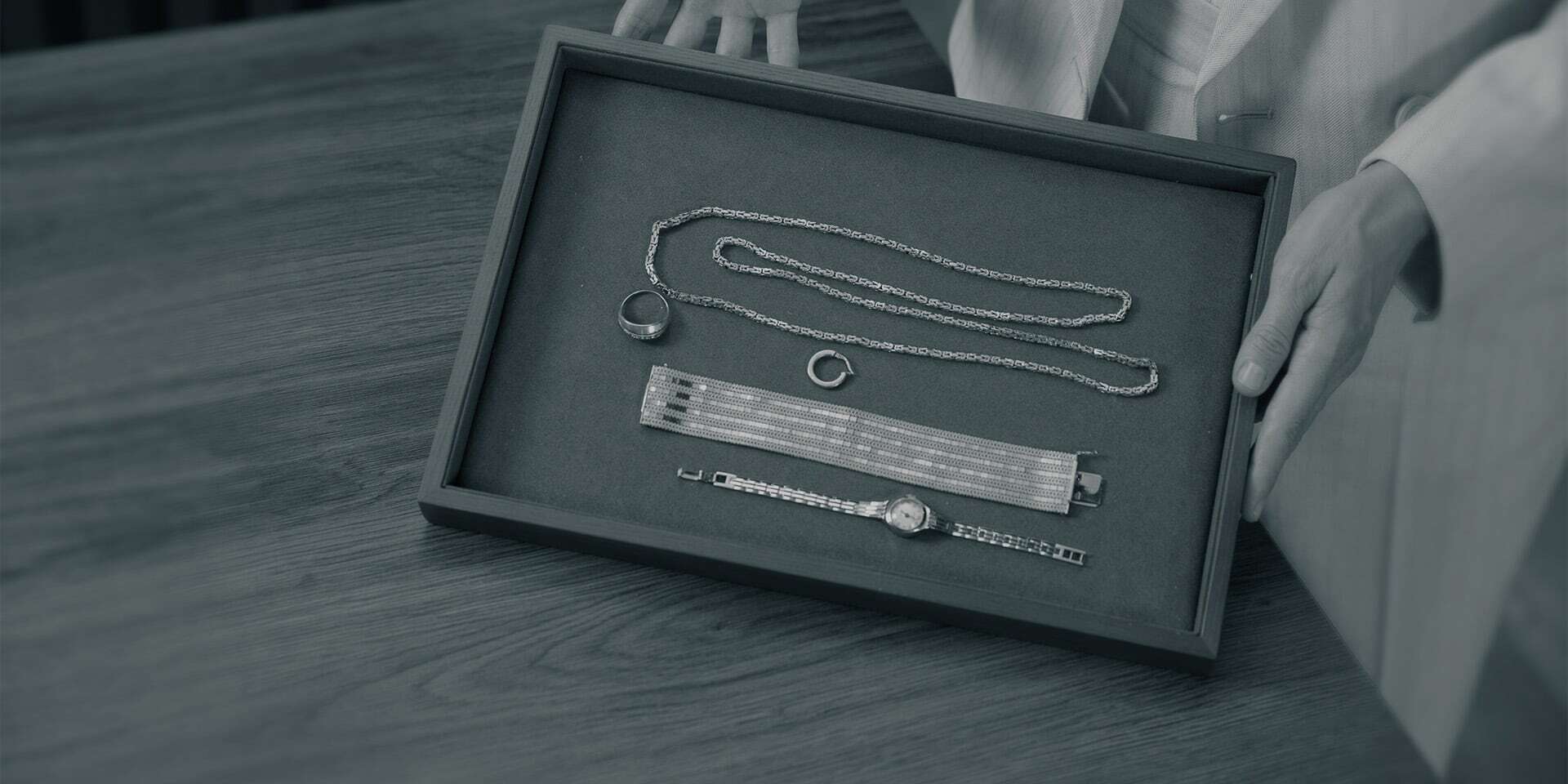 Degussa-Mitarbeiter prüft Schmuckstücke wie Ketten, Ringe und Uhren bei einem Ankaufsgespräch