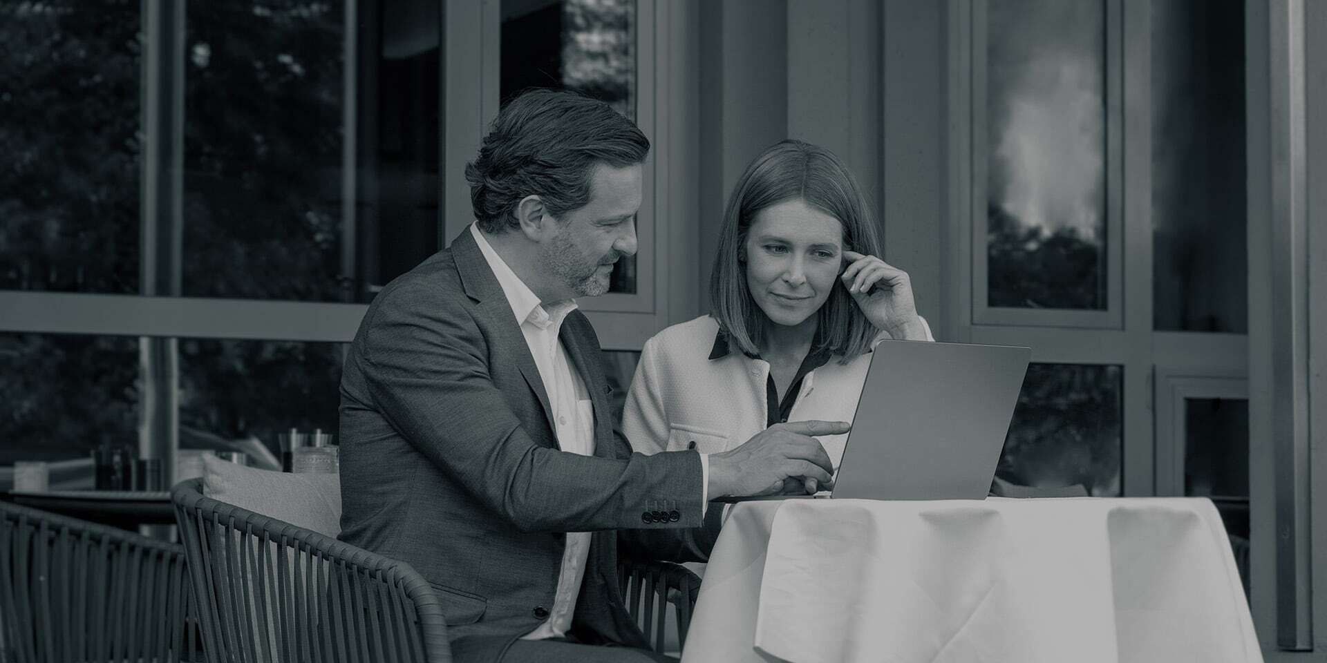 Kundin lässt sich von einem Degussa-Berater zum sicheren Wertlager beraten, beide blicken auf einen Laptop