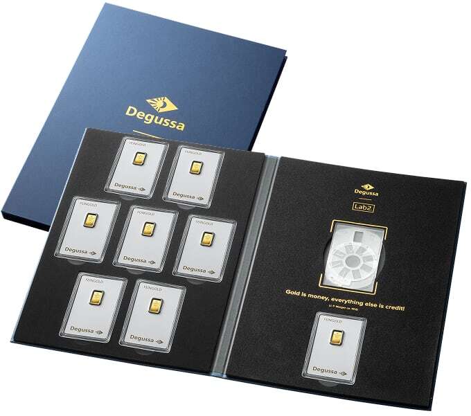 Aufgeklapptes Degussa-Geschenketui mit sieben 1-Gramm-Goldbarren links und einer Gold-Card-Blisterkarte rechts, daneben die geschlossene blaue Hülle mit Degussa-Logo.