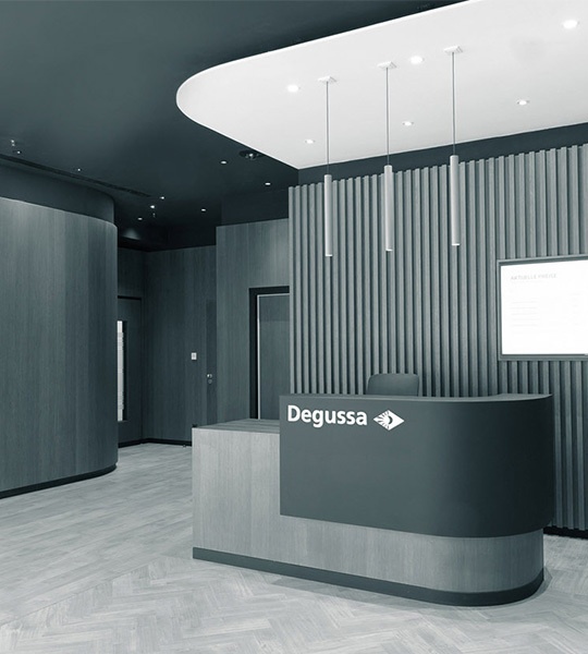 Moderner Empfangsraum mit holz-getäfelten hohen Wänden und einem Tresen auf dem das Degussa-Logo eingraviert ist
