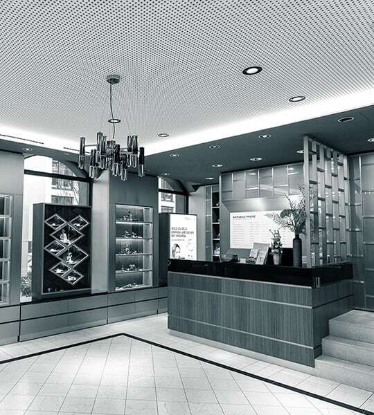 Empfangsbereich mit Tresen und verschiedenen Ausstellungsregalen und Vitrinen, die mit einem sanften Licht versehen sind