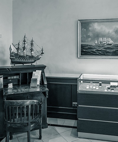 Ecke des Empfangsbereichs, in der ein altes Schreibpult steht, auf dem ein aufwendig erstelltes Miniaturschiff steht