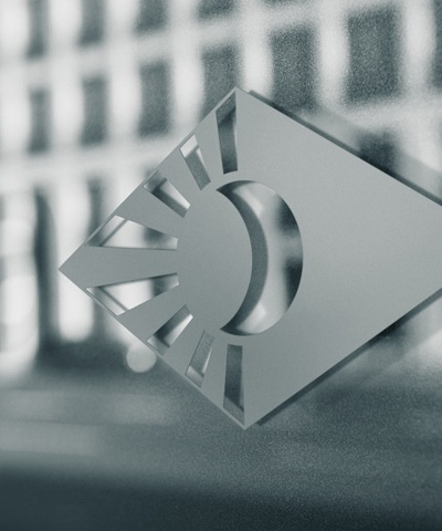 Nahaufnahme des Degussa-Logos (stilisierte Sonne in Raute) als goldene Applikation auf einer Glasfläche