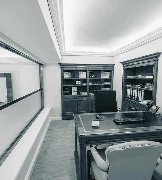 Beratungsbüro mit großem Schreibtisch aus dunklem Holz, Ledersesseln und zwei Bücherschränken