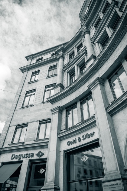 Außenansicht des Degussa-Gebäudes in München (Promenadeplatz) mit gewölbter Fassade, Säulen und dem Schriftzug \"Gold & Silber\"