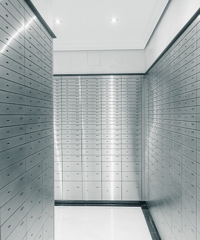 Innenansicht eines Tresorraums mit langen Reihen von gleichmäßig angeordneten Schließfächern an den Wänden