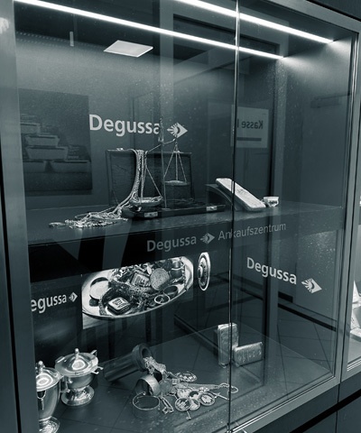 Detailaufnahme einer beleuchteten Vitrine mit Gold- und Silberschmuck, einer Waage und weiteren Edelmetallprodukten