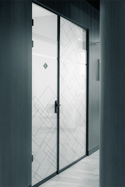 Gangansicht mit einer modernen, doppelflügeligen Glastür, die mit einem geometrischen Muster versehen ist