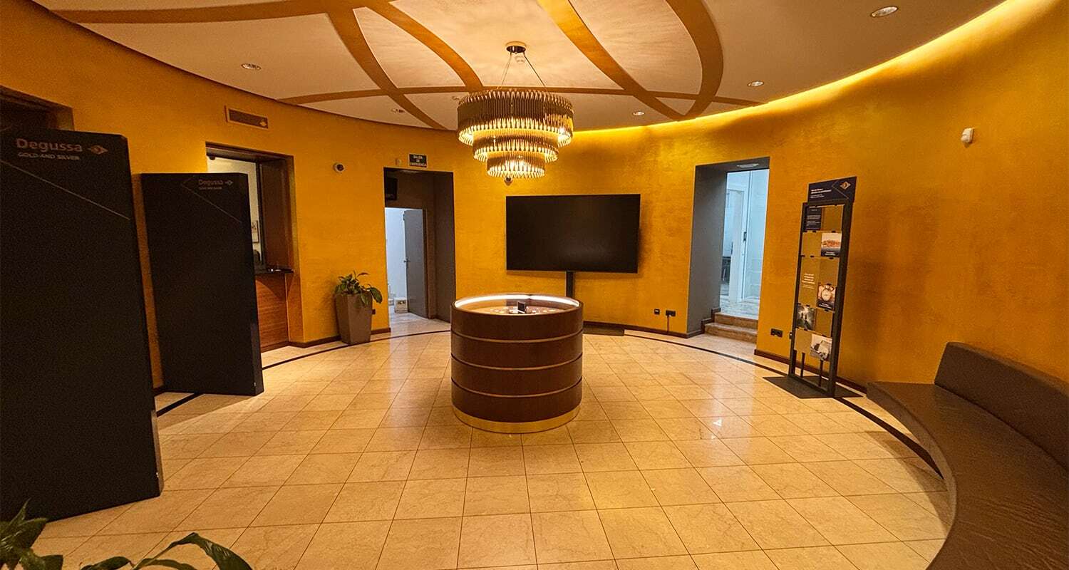 Modern sales area of the Degussa branch in Madrid with golden walls and a display case.