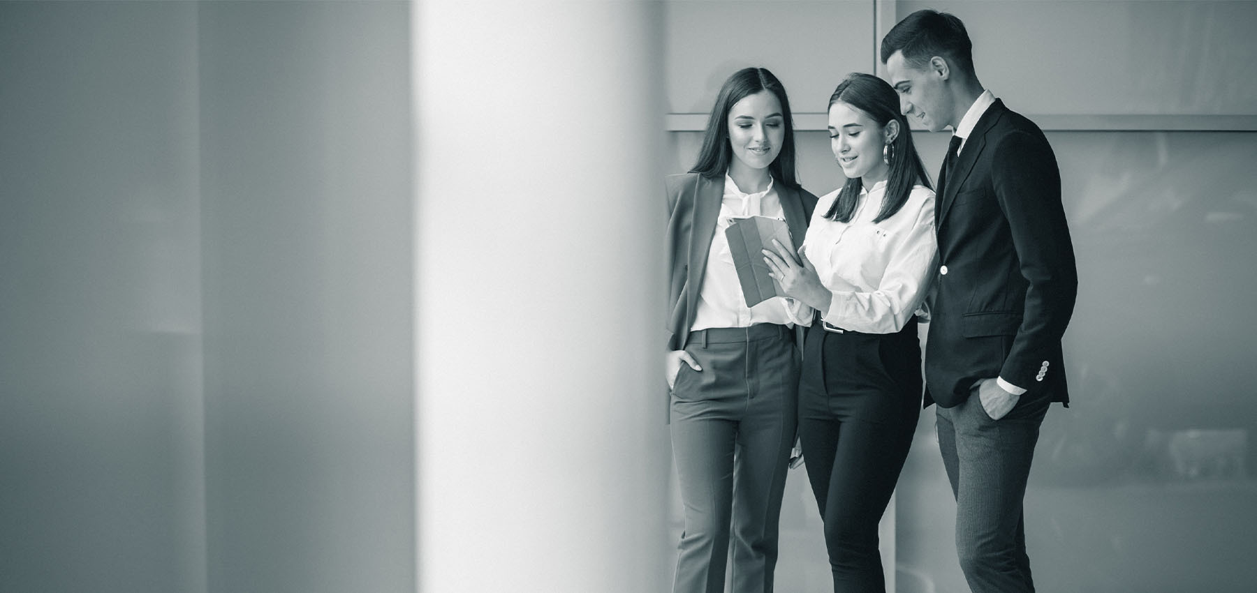 Drei junge Geschäftsleute stehen zusammen und schauen gemeinsam auf ein Tablet.